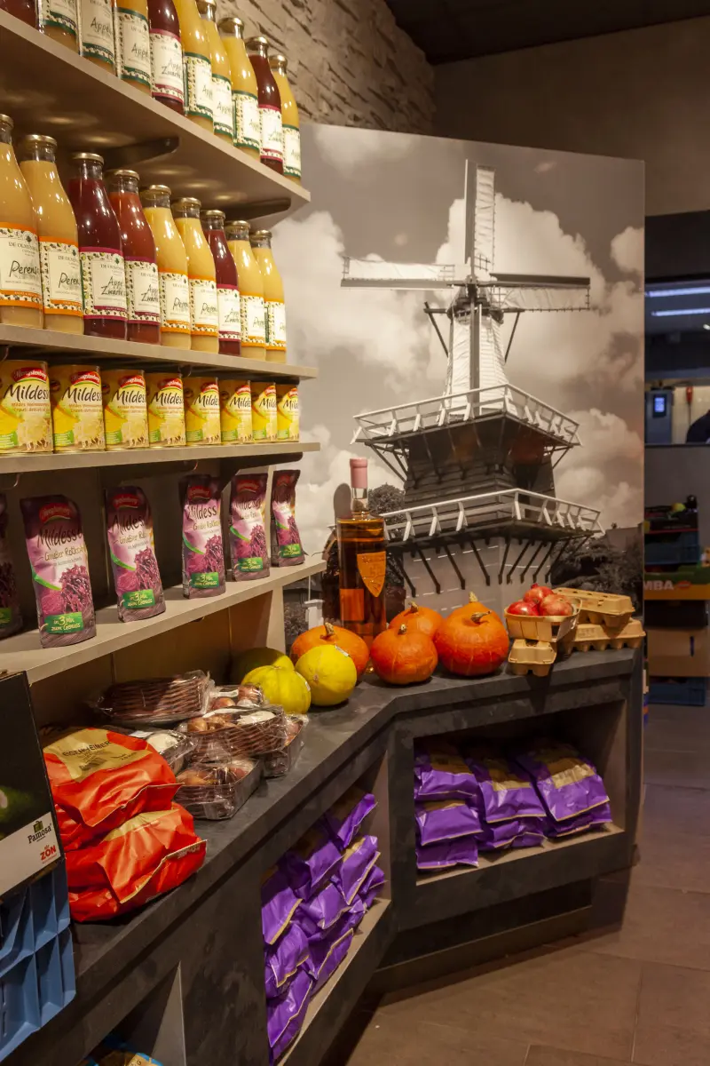 Hoek van de winkel met schappen vol flessen sap, pompoenen en fruit